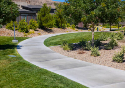 A community concrete jogging and walking trail with gravel and mixed plantings