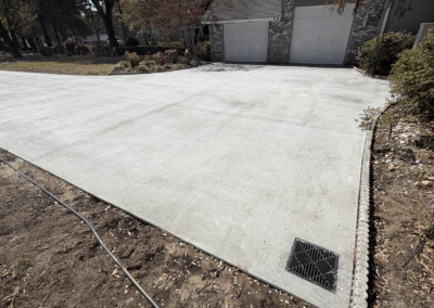 New concrete driveway with French drain at a grey brick home in South Carolina